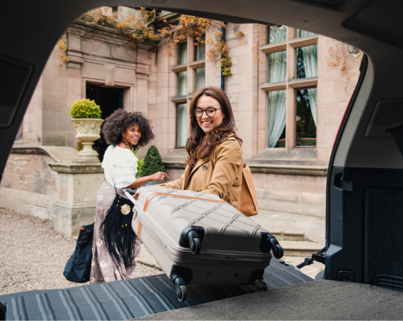 Two Young Female Teachers Traveling In Europe, Taking Their Luggage Out Of The Car.