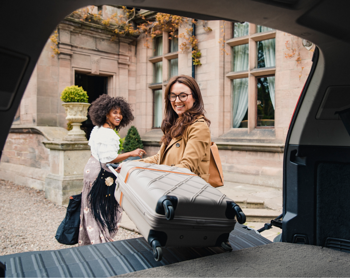 Two young female teachers traveling in Europe, taking their luggage out of the car.